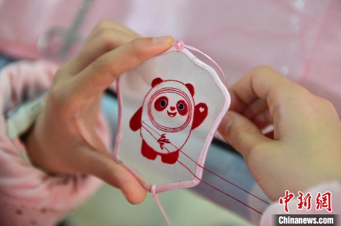 圖為一名小學(xué)生正在繡制2022年北京冬奧會(huì)吉祥物“冰墩墩”形象?！∮髟屏?攝