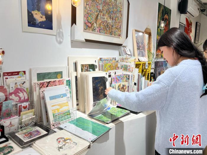 圖為藝術(shù)品商店內(nèi)，顧客挑選插畫作品。　鐘旖 攝