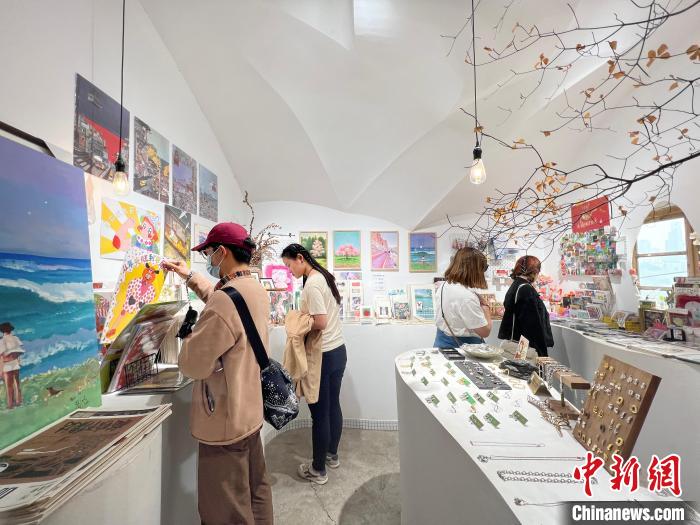 圖為藝術(shù)品商店內(nèi)，顧客挑選插畫作品?！＄婌?攝