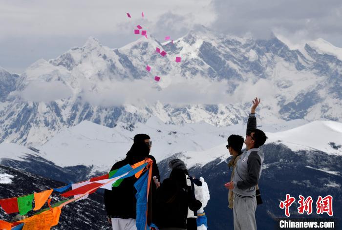 圖為5月14日，游客在西藏林芝色季拉山觀景臺(tái)拋灑“隆達(dá)”(風(fēng)馬旗，藏族民眾的一種祈福方式)?！±盍?攝