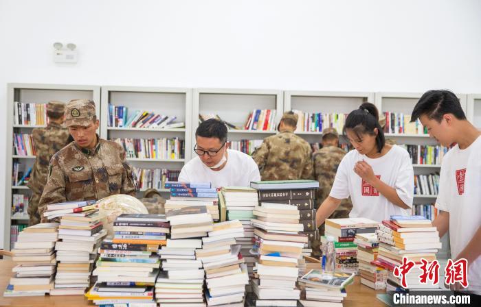 圖為志愿者們和邊防戰(zhàn)士整理圖書?！詵| 攝