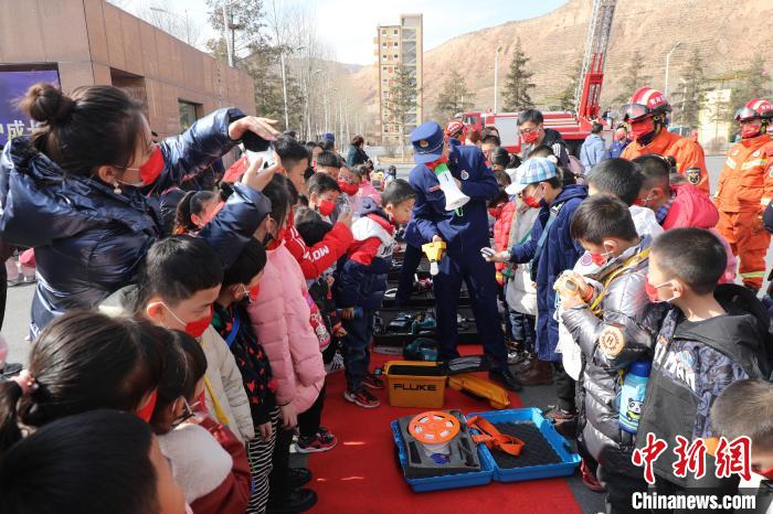 圖為小朋友們聽(tīng)消防員講解消防器材?！铨埥?攝