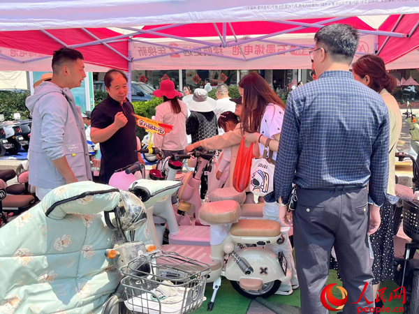 某電動自行車品牌工作人員向消費者介紹以舊換新相關(guān)情況。人民網(wǎng)記者 杜燕飛攝