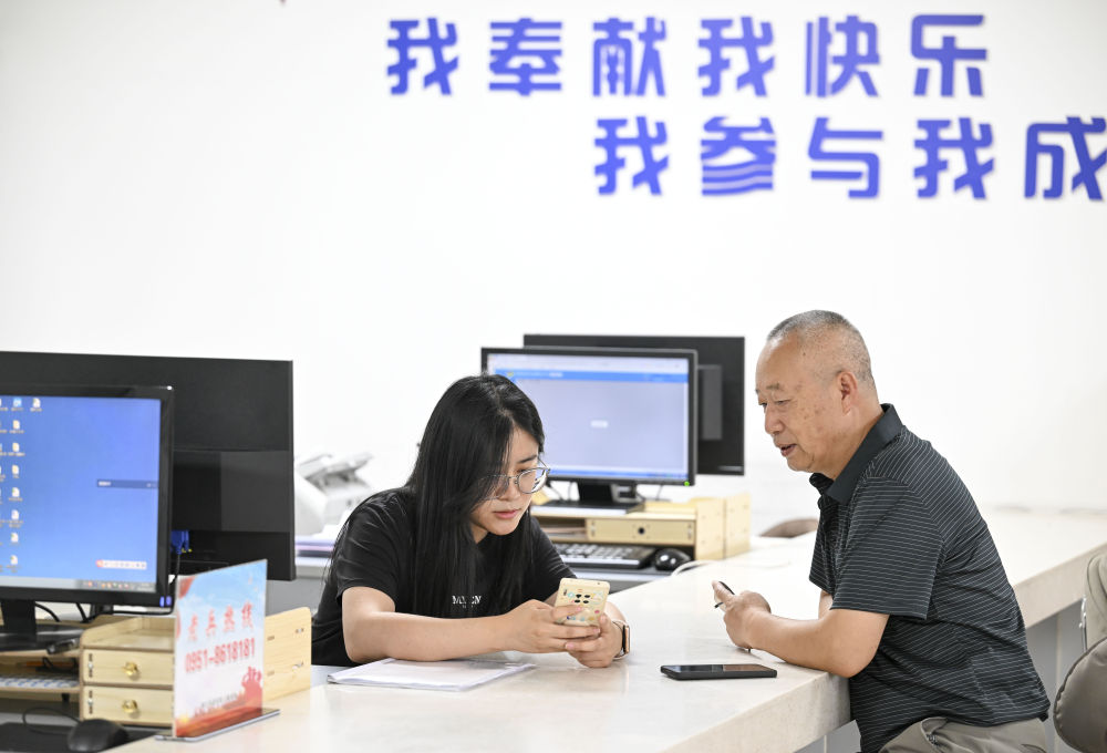 2024年6月20日，在寧夏銀川市金鳳區(qū)長城花園社區(qū)黨群服務(wù)中心，工作人員幫助居民辦理業(yè)務(wù)。圖片來源 新華社