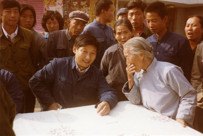 1983年，時(shí)任河北正定縣委書記的習(xí)近平（前排居中），臨時(shí)在大街上擺桌子聽取老百姓意見。