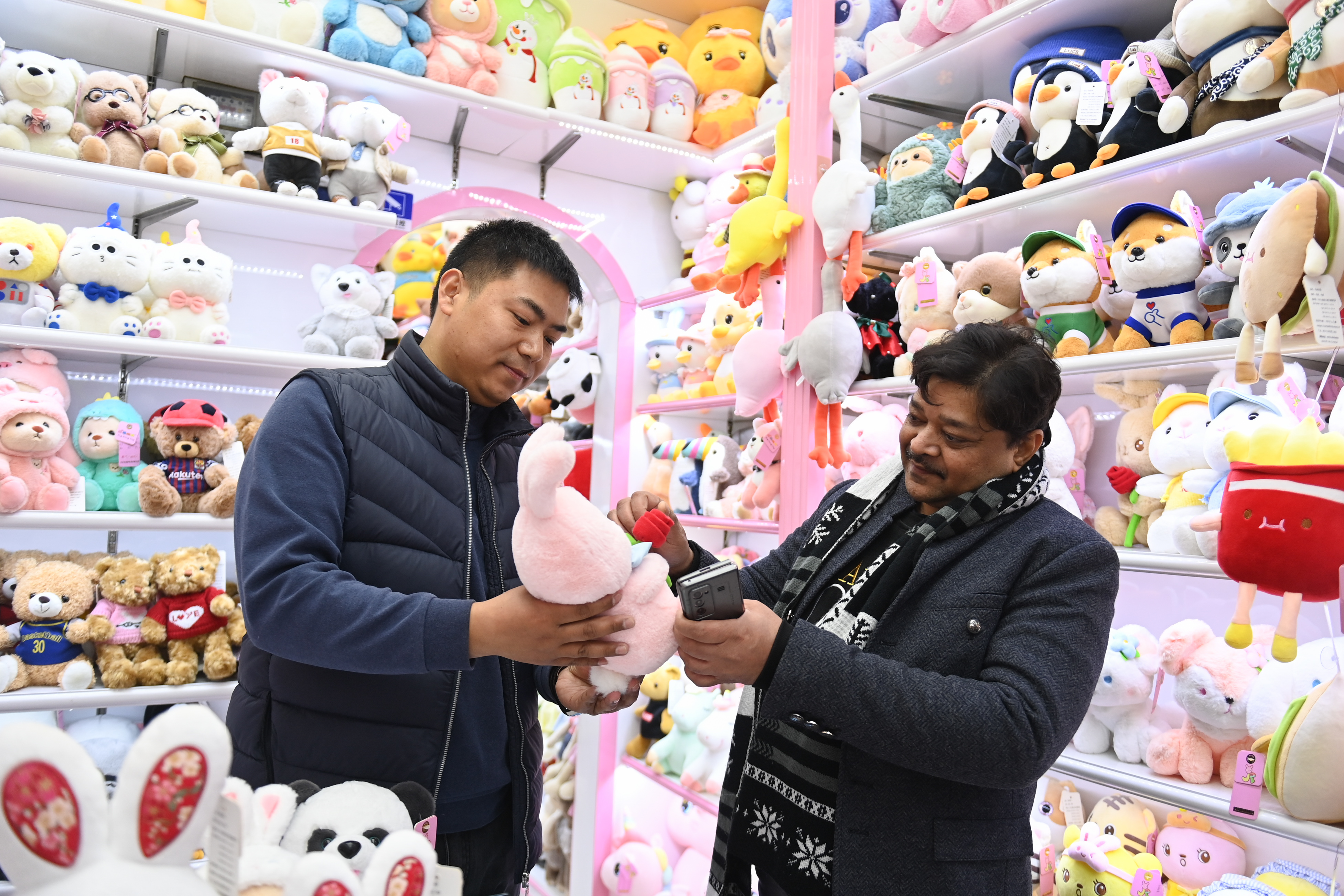 2023年2月2日，來自印度的客商（右）在義烏國際商貿城的一家玩具店鋪內選購。