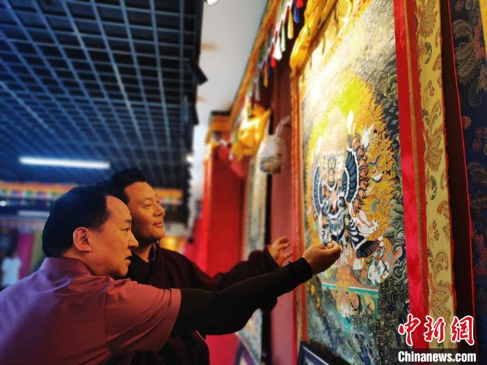 圖為久美尖措展示唐卡作品?！?zhí)砀?攝