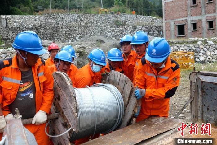 國網四川送變電公司搶險隊員將重達370公斤的鋼絞線搬上車?！⑾驸C 攝