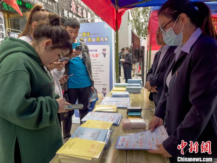 圖為工作人員正在向路過(guò)市民介紹國(guó)家反詐中心軟件的功能。　謝牧 攝