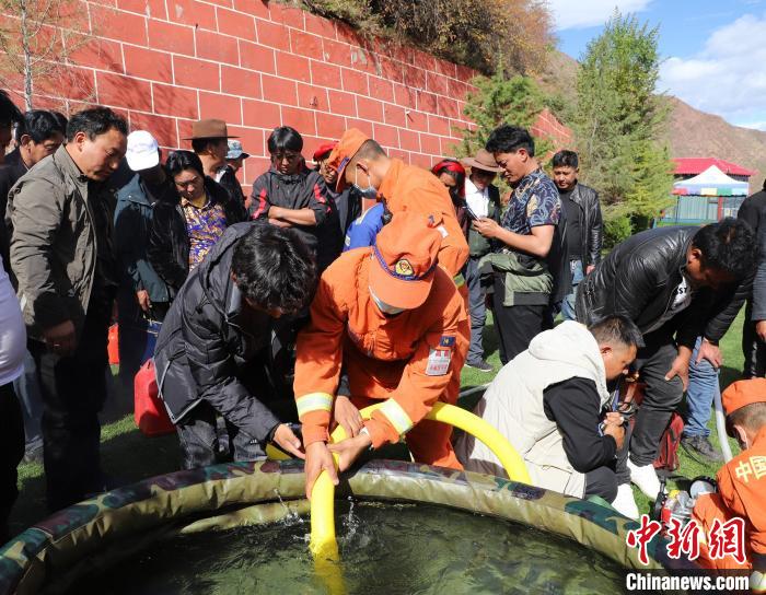 圖為森林消防員為護(hù)林員講解滅火裝備的使用方法?！〔际猩窒乐ш?duì) 供圖