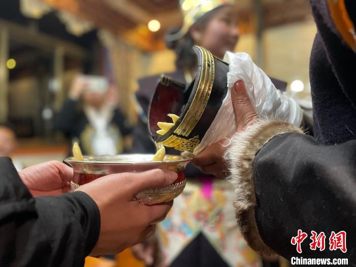圖為主人在碗中斟滿青稞酒?！∪轿木?攝