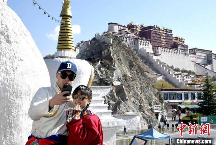 4月17日，游客身著藏式元素服裝在拉薩布達(dá)拉宮觀景臺(tái)拍照留念?！±盍?攝