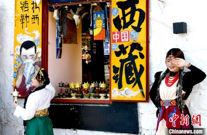4月17日，游客身著藏式元素服裝在拉薩八廓街拍照留念。　李林 攝
